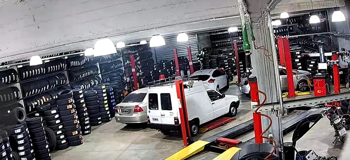 Interior del taller de Neumáticos Drago con autos en elevadores y estanterías de cubiertas